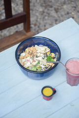 Blue bowl on a blue wooden table with red juice under natural daylight. A vibrant and fresh food scene, highlighting healthy, colorful, and refreshing elements in an outdoor setting.