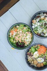 Bowl with refreshing food and fresh vegetables on a blue table under daylight. A bright, colorful,...