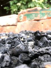 Charcoal piles on ground near brick wall in outdoor setting