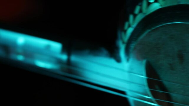 Extreme macro shot of a traditional ethnic stringed instrument. The camera slowly reveals details of the tuning pegs, strings, and fretboard with moody lighting.