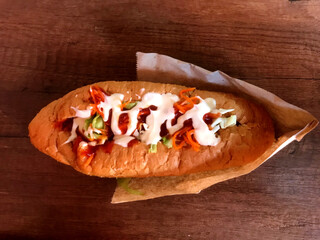 Tasty sandwich topped with vegetables and sauces on a platter