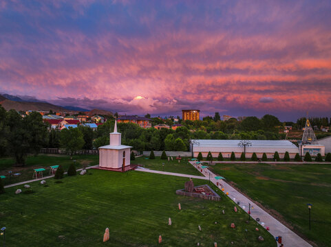 Aerial view of the Rukh Ordo Cultural Center in Cholpon Ata, Kyrgyzstan, with its unique architecture set against a dramatic pink and purple sunset sky