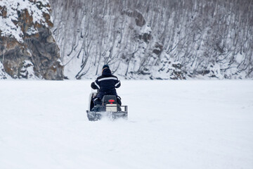 A man is riding a snowmobile on a snowy road