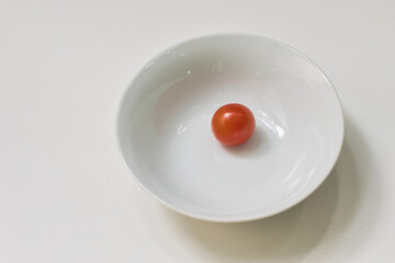 einzelne cocktail-tomate in einer weissen pozellanschale