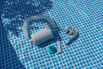 Pool filter and accessories on the bottom of the empty pool. Close-up in bright sunlight.