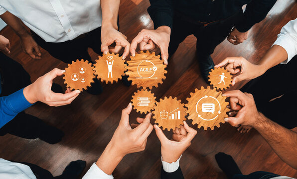 This image showcases a diverse group of hands holding gears with icons, representing teamwork and collaboration in business strategies and agile project management efforts. Amity