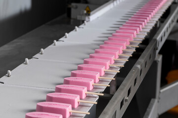 Obraz premium Close-Up of Pink Ice Cream Popsicles on Industrial Production Line – Frozen Dessert Manufacturing