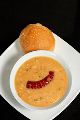 Grilled sausages with baked white beans in white plate over black stone background. Top view, flat lay