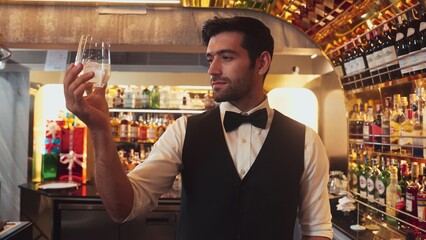 Smart bartender chilling glass with ice for serving drink to customer at beverage bar counter welcome drink with charm professionalism making great first impression greeting guess at club. Vinosity.
