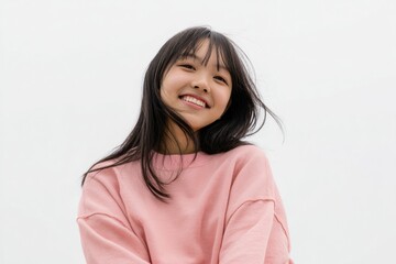 Fototapeta premium A smiling Japanese woman, wearing pastel pink cloth, expresses joy in her portrait, complemented by a white background that creates an inviting mood.