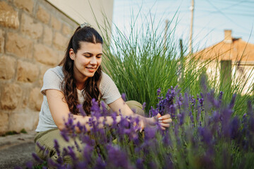 Young caucasian woman is cutting lavender at her home garden during the day  © Dusan