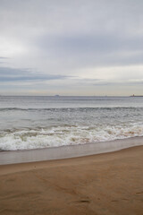 White foamy waves in a beautiful blue sea. In the distance, silhouettes of ships can be seen sailing near the coast of Gdansk on the Baltic Sea. Wave after wave rolled onto the shore. Background.