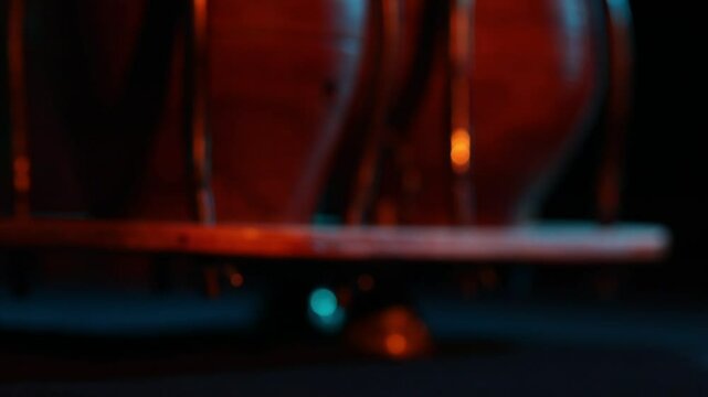 A cinematic close-up of Latin timbale drums under dramatic red and blue stage lighting. The camera tilts up and pulls focus to an atmospheric, blurry shot.