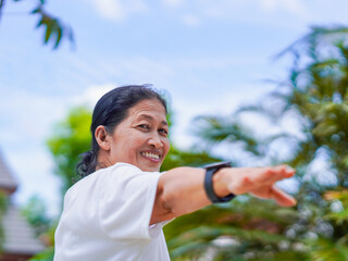 Happy asian senior woman active stretching use smart watch fitness tracker for health care in park....