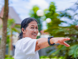 Happy asian senior woman active stretching use smart watch fitness tracker for health care in park....