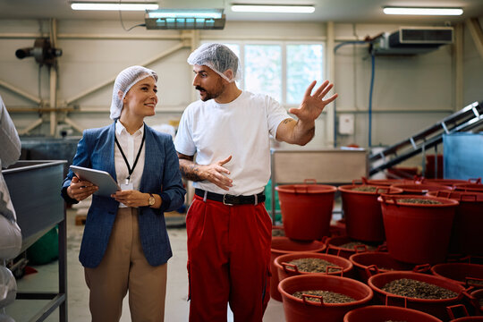 Happy female company manager talking to a worker while visiting food processing plant.