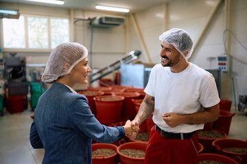 Happy food processing plant worker greeting a female manager in a factory.