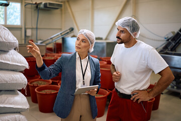 Food factory manager and worker examining stock of goods in storage room.
