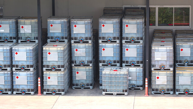 Chemical liquid IBC bulk containers stacked on the floor in front of storage warehouse chemistry in industrial factory area