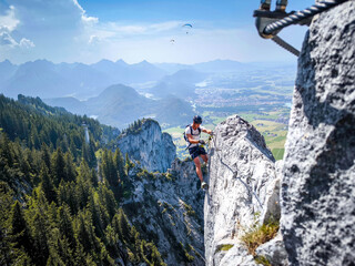 Climber On Fingersteig Via Ferrata Near Tegelberg: Adventurer Traversing Narrow Ridge With Harness...
