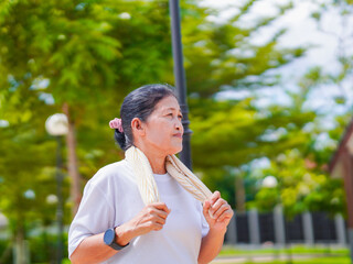 Asian senior woman happy smile  walking warm up exercise use smartwatch fitness tracker. Elderly care female activity jogging or running park for wellness health. Healthy lifestyle workout cardio 