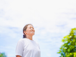 Happy Asian senior woman standing smile in park holiday for concept healthy lifestyle and meditation. Elderly care female active exercise enjoy feeling yoga, health care, freedom. Wellness mindfulness