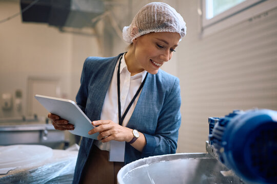 Quality control inspector using touchpad while supervising food processing in a factory.