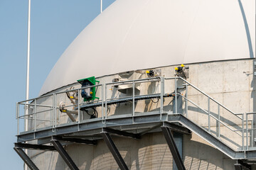 Closeup on new biogas facility. White dome with technical equipment under a blue sky.