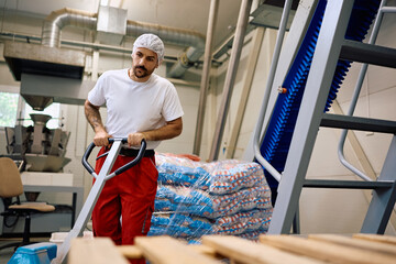 Factory plant worker moving packages with pallet jack.
