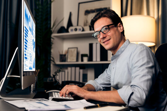 Smart businessman analyzing business paragraph dynamic database marketing analysis plan surrounded paper sheet and pc monitor report to compare with document data at home office at night. Pecuniary. - Powered by Adobe