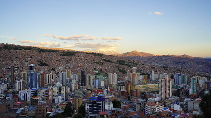 Aerial views of La Paz, Bolivia featuring the cable car system, city sprawl, and majestic snow-capped Andes mountains in the background.