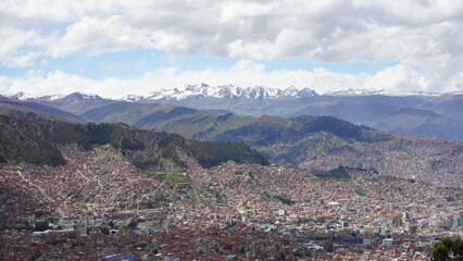Aerial views of La Paz, Bolivia featuring the cable car system, city sprawl, and majestic snow-capped Andes mountains in the background.