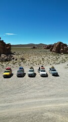 Convoy of 4x4 vehicles parked in Bolivia&rsquo;s surreal Rock City desert landscape, surrounded by dramatic stone formations under a clear sky