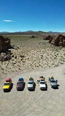 Convoy of 4x4 vehicles parked in Bolivia&rsquo;s surreal Rock City desert landscape, surrounded by dramatic stone formations under a clear sky