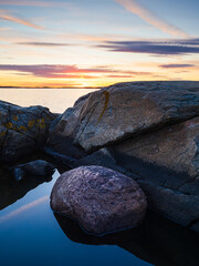Sunset over coastal rocks near Gothenburg, showcasing vibrant colors and tranquil reflections in the water