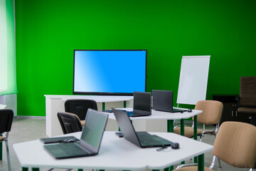 School desks with laptops in an empty modern classroom