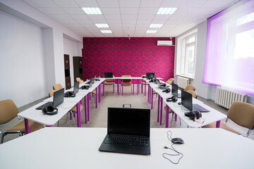 School desks with laptops in an empty modern classroom