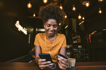 Smiling woman using smartphone and credit card during online payment in cafe