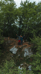 Fototapeta premium Couple and two dogs on rocky forest viewpoint on Ovcar mountain in Serbia, spring. Aerial view from drone. Hiking in Serbia in spring time