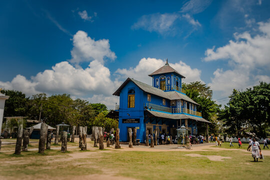 Devinuwara Uthpalawanna Sri Vishnu Maha Dewalaya in Sri Lanka &ndash; vibrant blue temple with visitors and ancient stone pillars, captured on a sunny day with Nikon D7500