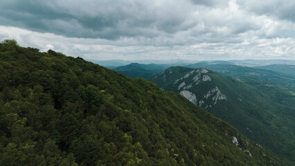 Fototapeta premium Aerial view of dense forest and steep cliffs in Ovcar mountain. Serbia country nature under cloudy spring sky