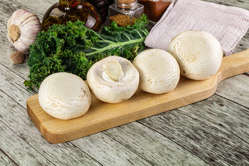 White champignon mushrooms heap over board