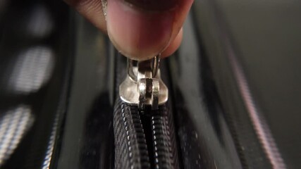 Man zipping up travel suitcase close-up. Close-up of hand zipping a black suitcase.
