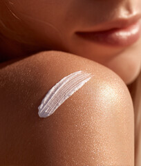 Fototapeta premium Female shoulder with moisturizing cream swatch on the skin, close-up 