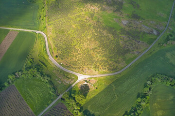 Winding roads through fields with sunrays, drone aerial view.