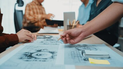 A vibrant office scene showcasing team collaboration on architectural plans, highlighting hands engaged in discussion over detailed sketches and project notes. SACTR