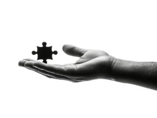 A close-up of a human hand elegantly holding a black puzzle piece, symbolizing problem-solving and creativity.