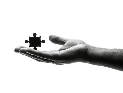 A close-up of a human hand elegantly holding a black puzzle piece, symbolizing problem-solving and creativity.