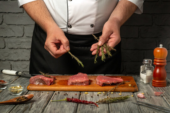 A chef stands at a wooden table, skillfully handling fresh cuts of meat and aromatic herbs. The setting creates an inviting atmosphere for a cooking demonstration focused on flavor enhancement