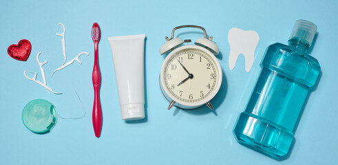 Set of oral hygiene products and items including red toothbrush, dental floss, mouthwash, alarm...